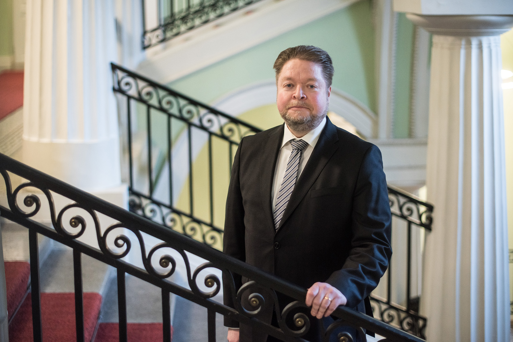 Substitute for the Deputy Chancellor of Justice Petri Martikainen wearing a suit and going up the stairs inside the Government Palace.